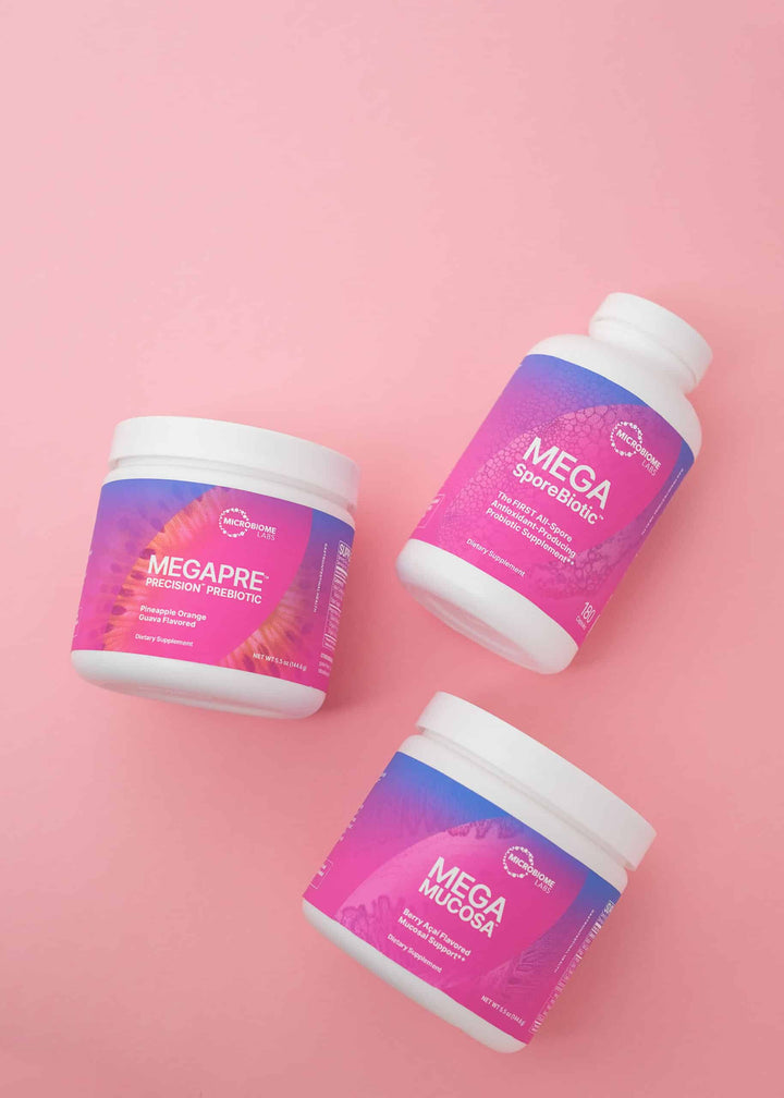 Microbiome Labs MegaMucosa Powder, MegaSporeBiotic, and MegaPre jars on a pink background.