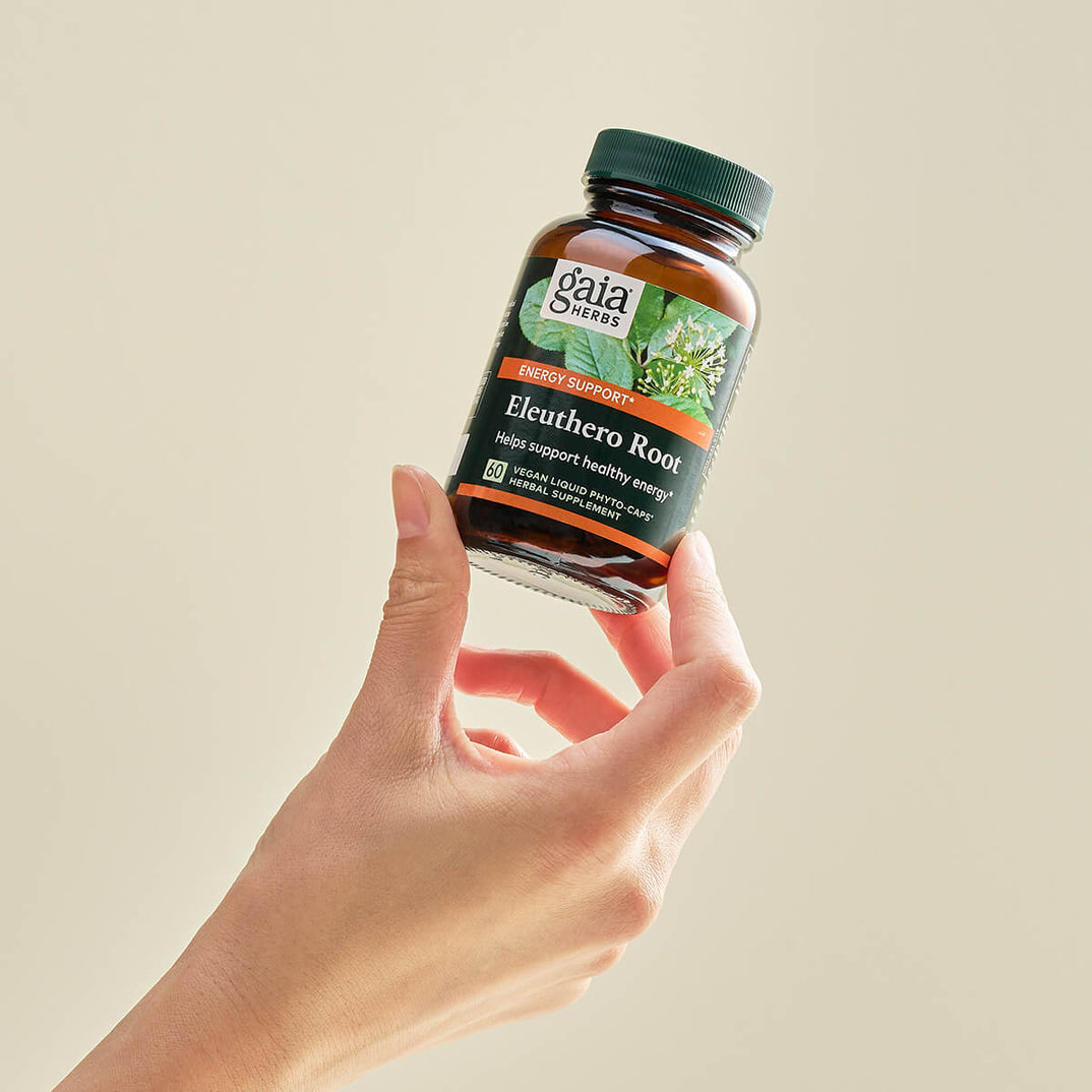 Hand holding Gaia Herbs Eleuthero Root 60 Capsules bottle for energy and stress support.