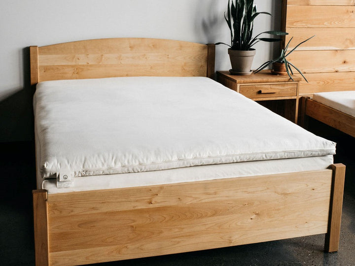 Holy Lamb Wool and Latex Mattress Topper on a wooden bed frame with natural decor.