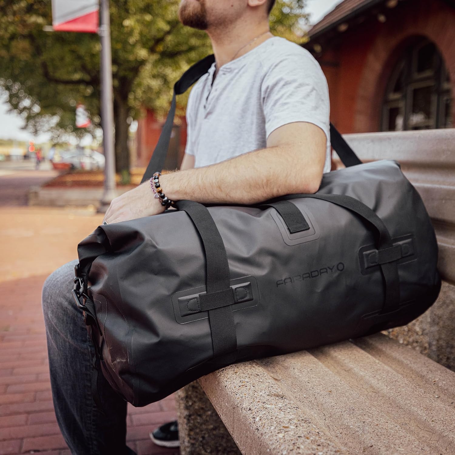 Faraday Dry Duffel Bag Stealth Black 55L sitting on a bench, showcasing its durable design and shielding capabilities.