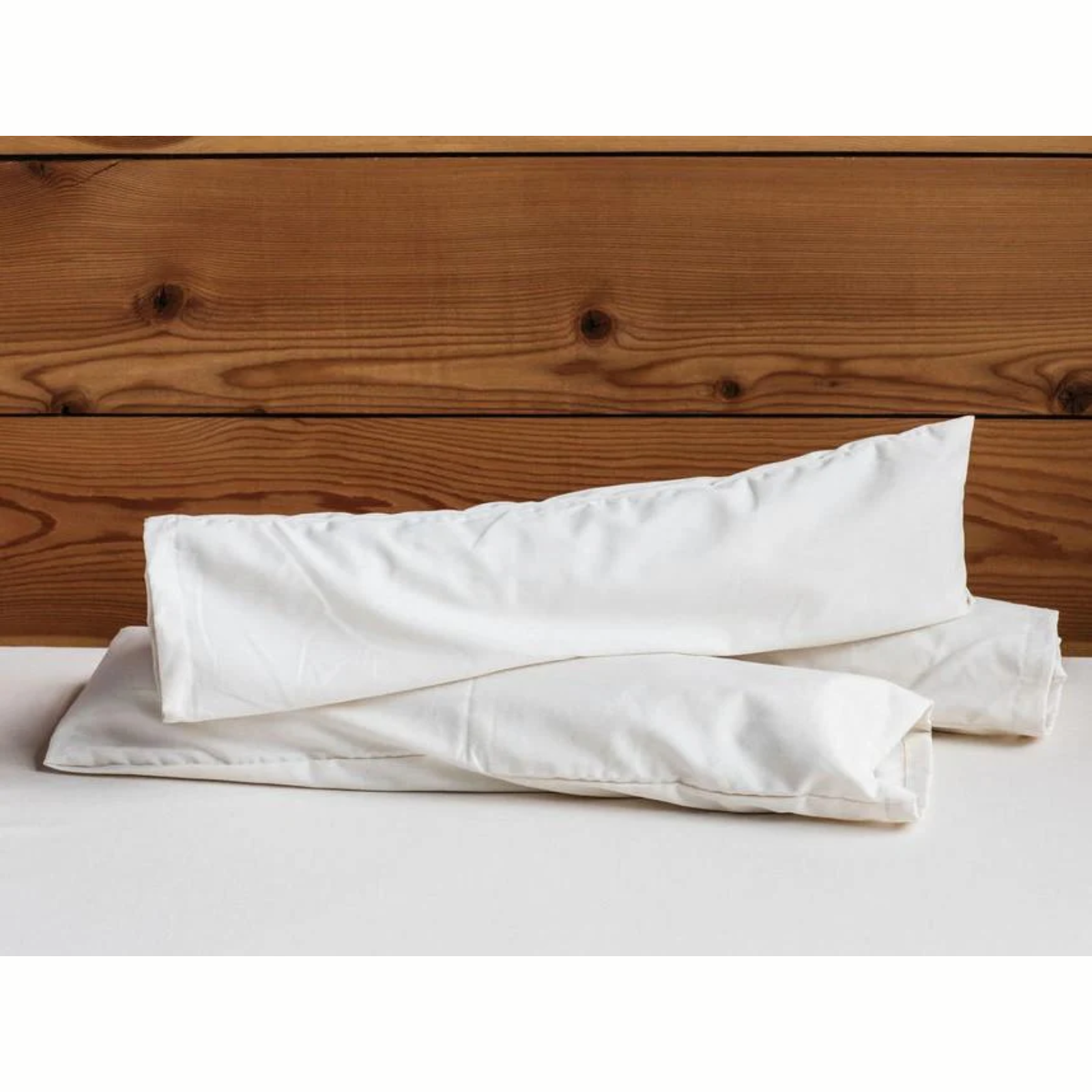Holy Lamb Organics Neck Roll Supportive Cushion for Sleep and Relaxation on a wooden surface.