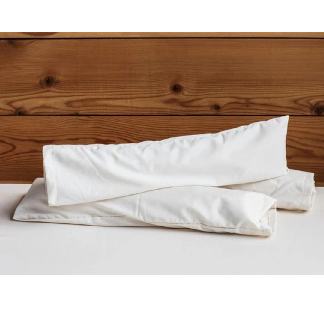 Holy Lamb Organics Neck Roll on a soft surface with a wooden backdrop, providing comfort and support for better sleep.