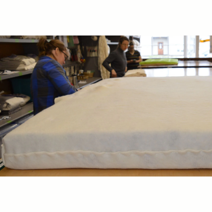 Holy Lamb Organics Wool &amp; Latex Mattress being crafted by artisans in a workshop, showcasing its natural materials.