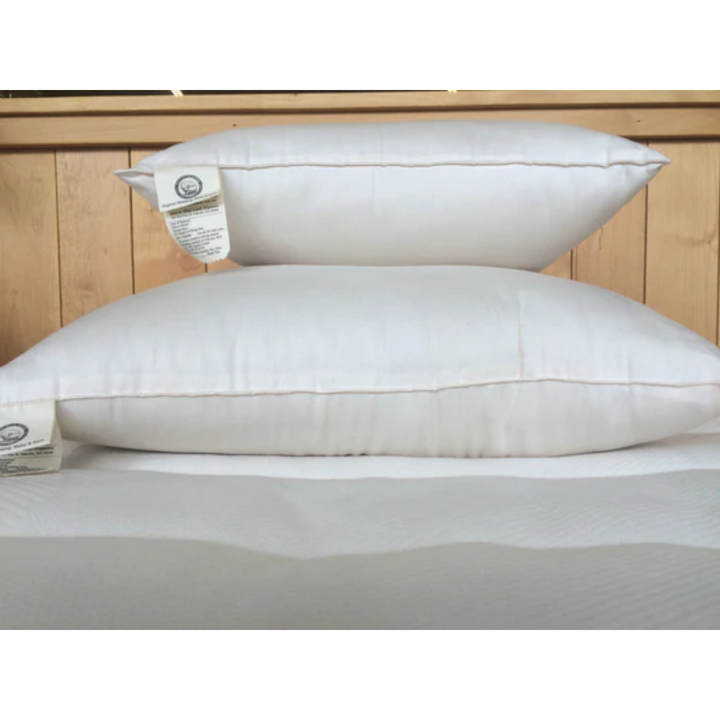 Holy Lamb Organics Throw Pillows in white, showcasing their comfortable and stylish design on a warm wooden backdrop.
