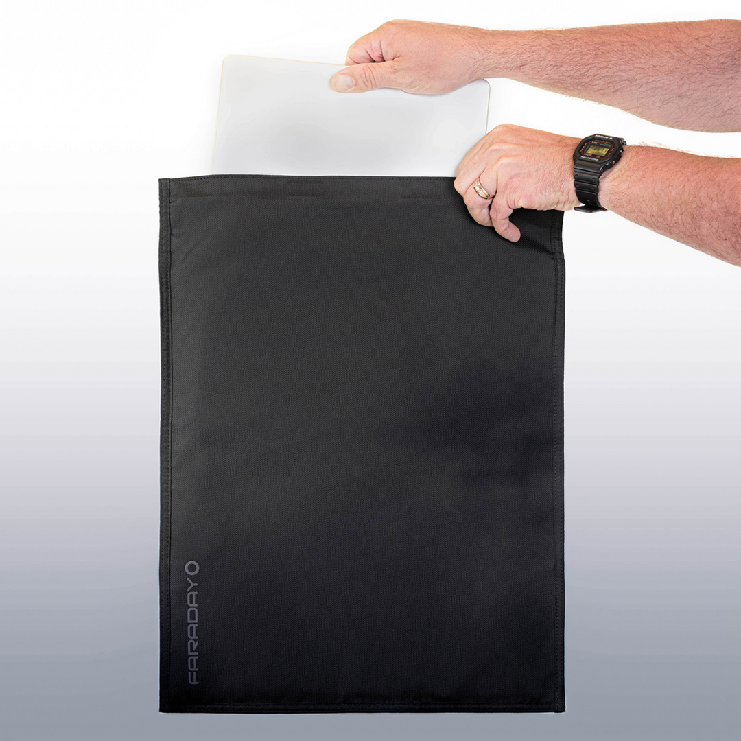 Person inserting a laptop into the Faraday Jacket Pro Cordura bag, showcasing its protective design and magnetic closure.