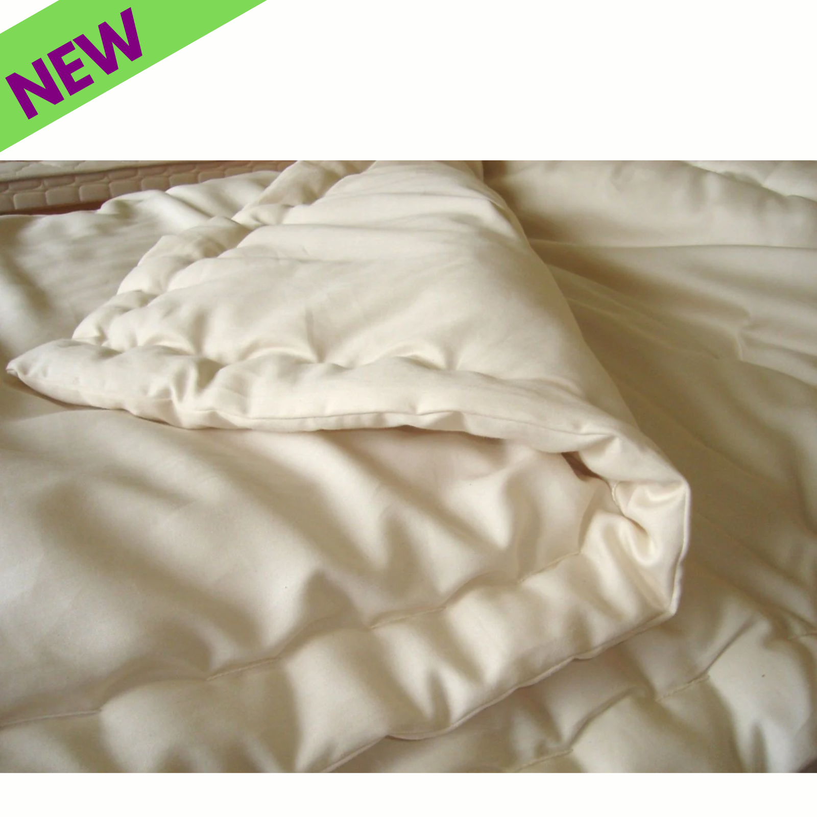 Holy Lamb Organics Wool Comforter in cream color folded on a bed with a 'NEW' label, 92" x 88" size.