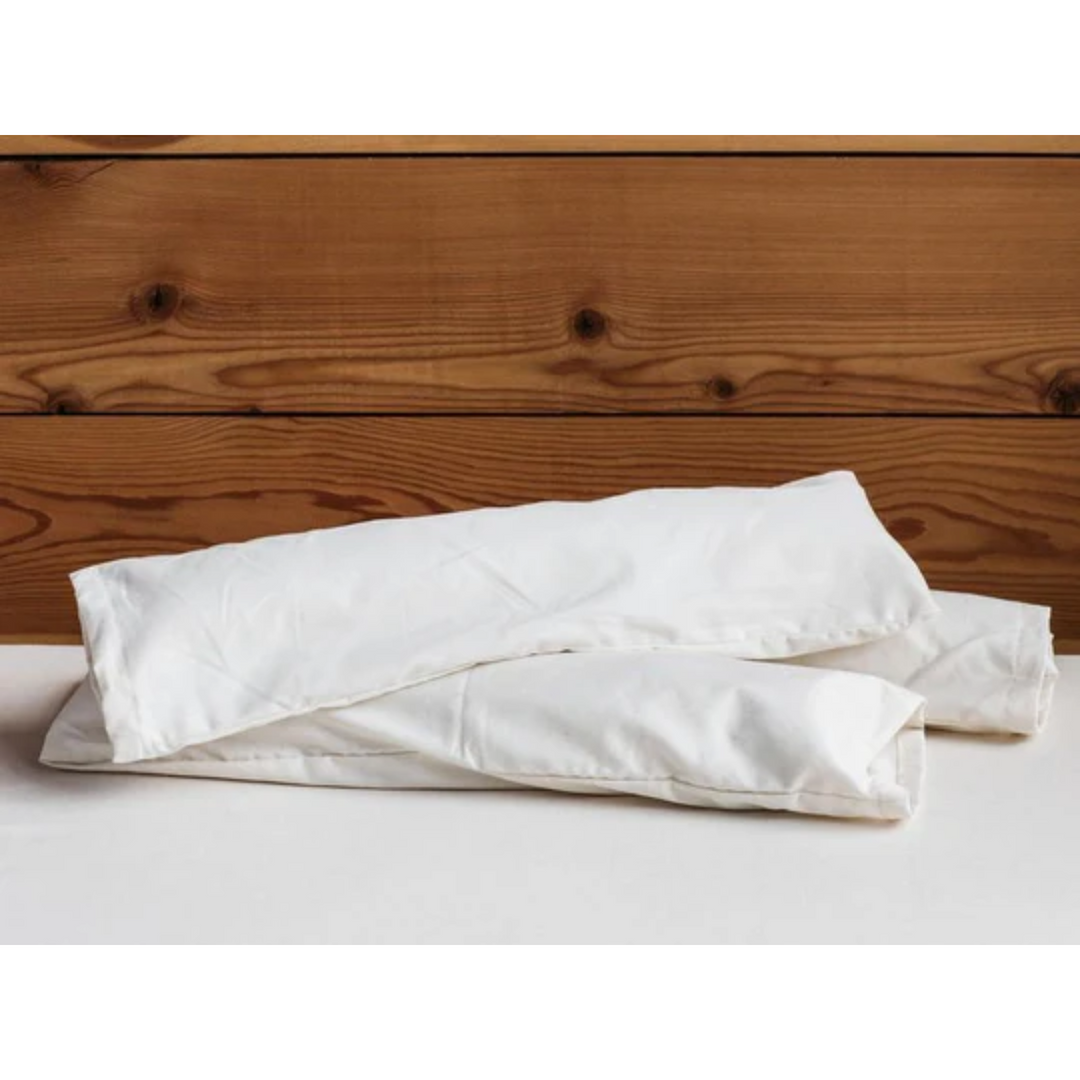 Holy Lamb Organics Neck Roll pillows placed on a wooden surface, showcasing their comfortable design and organic materials.