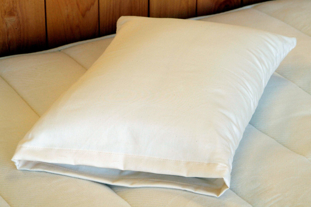 Holy Lamb Organics Travel Pillow in natural cotton and wool on a mattress, 12.5" x 17.5" for comfortable travel.