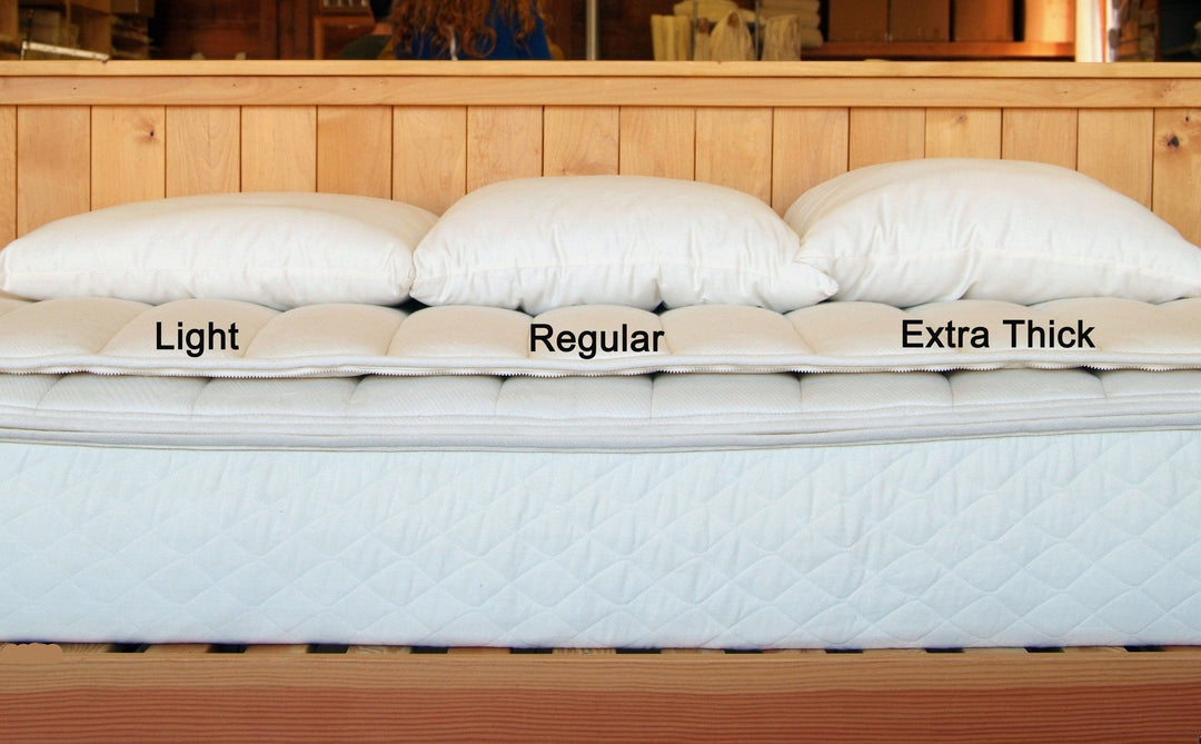 Image of Holy Lamb Bed Pillows showing Light, Regular, and Extra Thick options on a mattress.