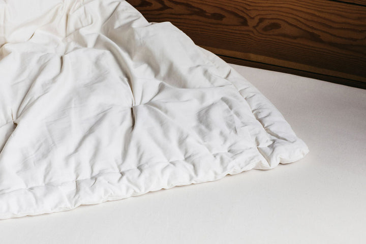 Holy Lamb Organics Wool Comforter on a bed, showcasing its luxurious texture and quality fabric.