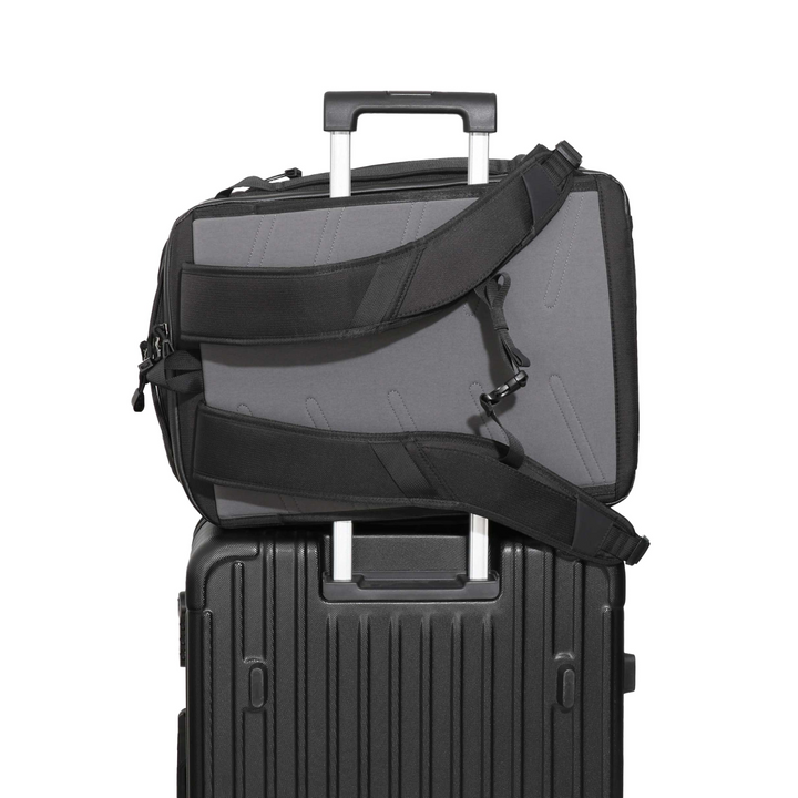 Faraday Jacket Pro CORDURA backpack secured on a rolling suitcase, showcasing its portability and convenience.