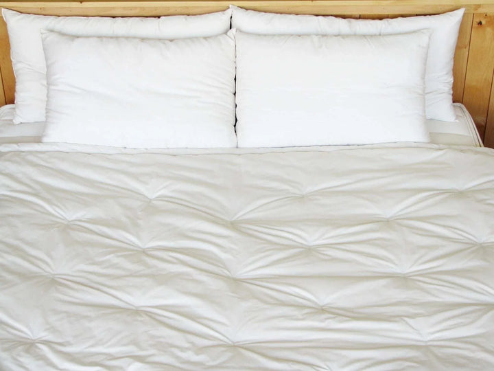 Holy Lamb Organics Comforter displayed on a bed with white pillows, showcasing its luxurious and sustainable design.