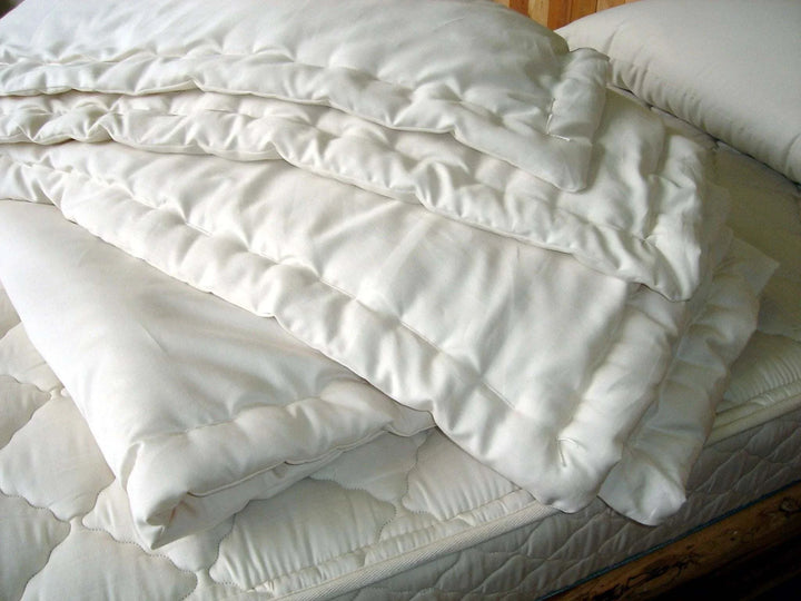 Holy Lamb Organics Comforter stacked on a bed, showcasing its organic wool filling and premium quality.
