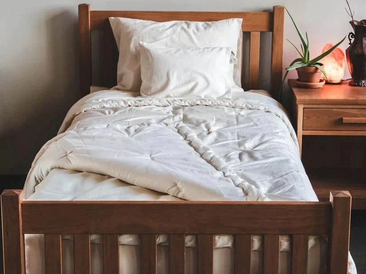 Holy Lamb Organics Comforter on a wooden bed, showcasing its organic wool design and cozy look.