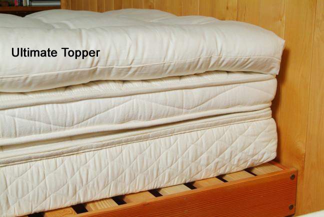 Holy Lamb Organics Quilted Mattress Topper stacked on a wooden platform showcasing plush layers for ultimate comfort.