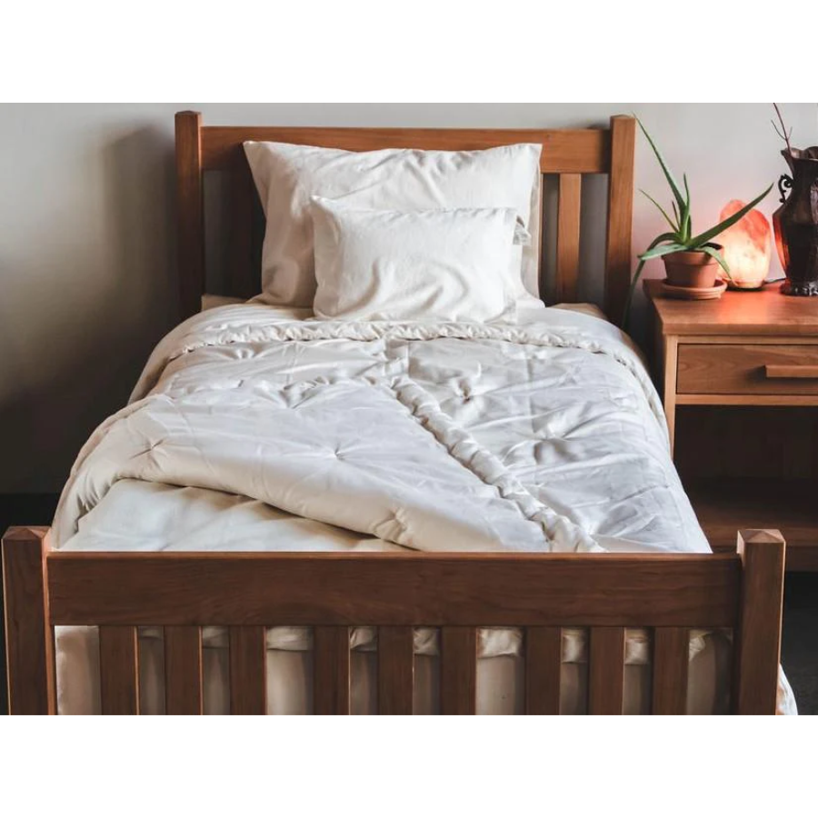Holy Lamb Organics Comforter on a bed with natural decor and cozy pillows in a minimalist bedroom setting.