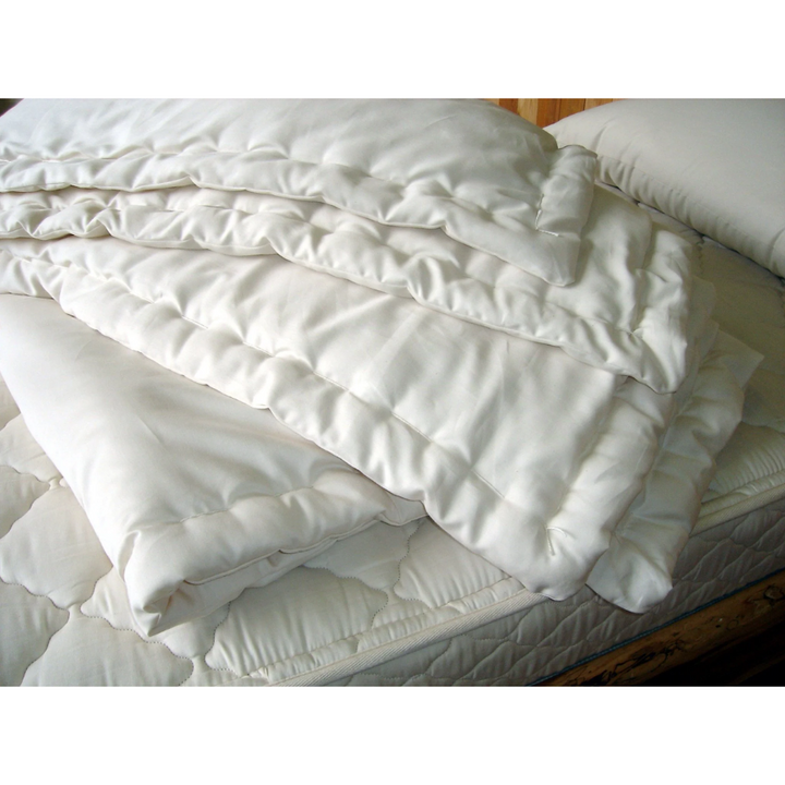 Holy Lamb Organics Comforter stacked on a bed, showcasing organic wool warmth in a full/queen size.
